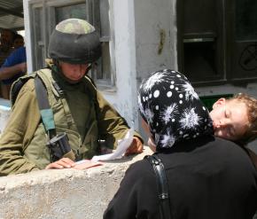 An IDF soldier examines a Palestinian woman's papers at the Beit Iba checkpoint outside Nablus in the West Bank