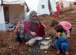 Refugees from the fighting in Syria prepare a meal outside their tent in a camp on the Syrian-Turkish border