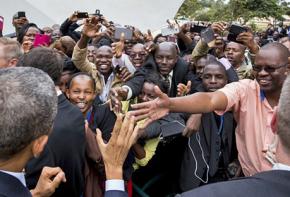 Barack Obama (front left) greeted by large crowds on his arrival in Kenya