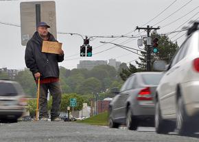 A homeless man stands at an intersection in Portland, Maine