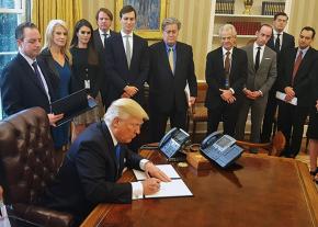 Trump signs an executive order surrounded by advisers and cabinet officials