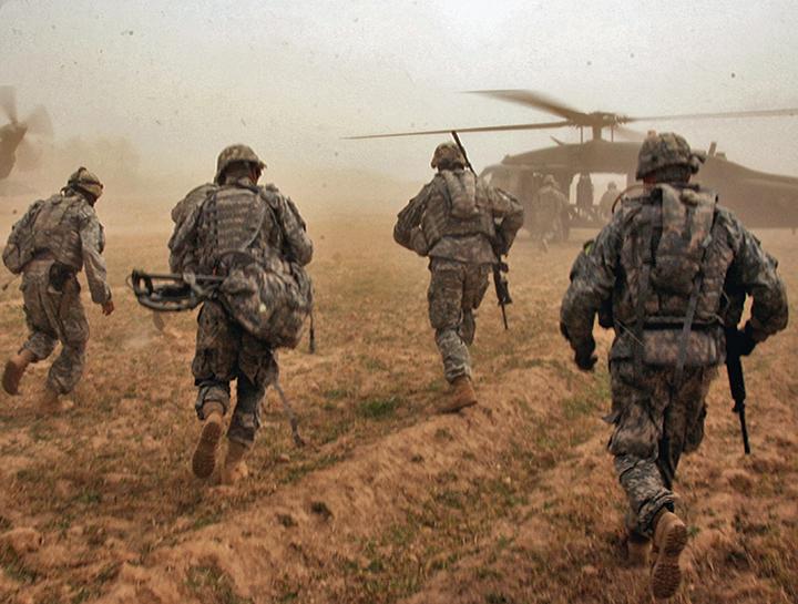 U.S. soldiers run toward Black Hawk helicopters after a search for weapons caches in Iraq