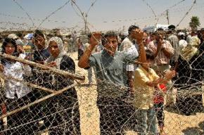 Palestinians wait behind barbed wire at the checkpoint at Rafah