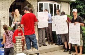 Anti-eviction activists attempt to block the door to an Addison home