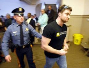 William Brown is led out of the town hall meeting by state police